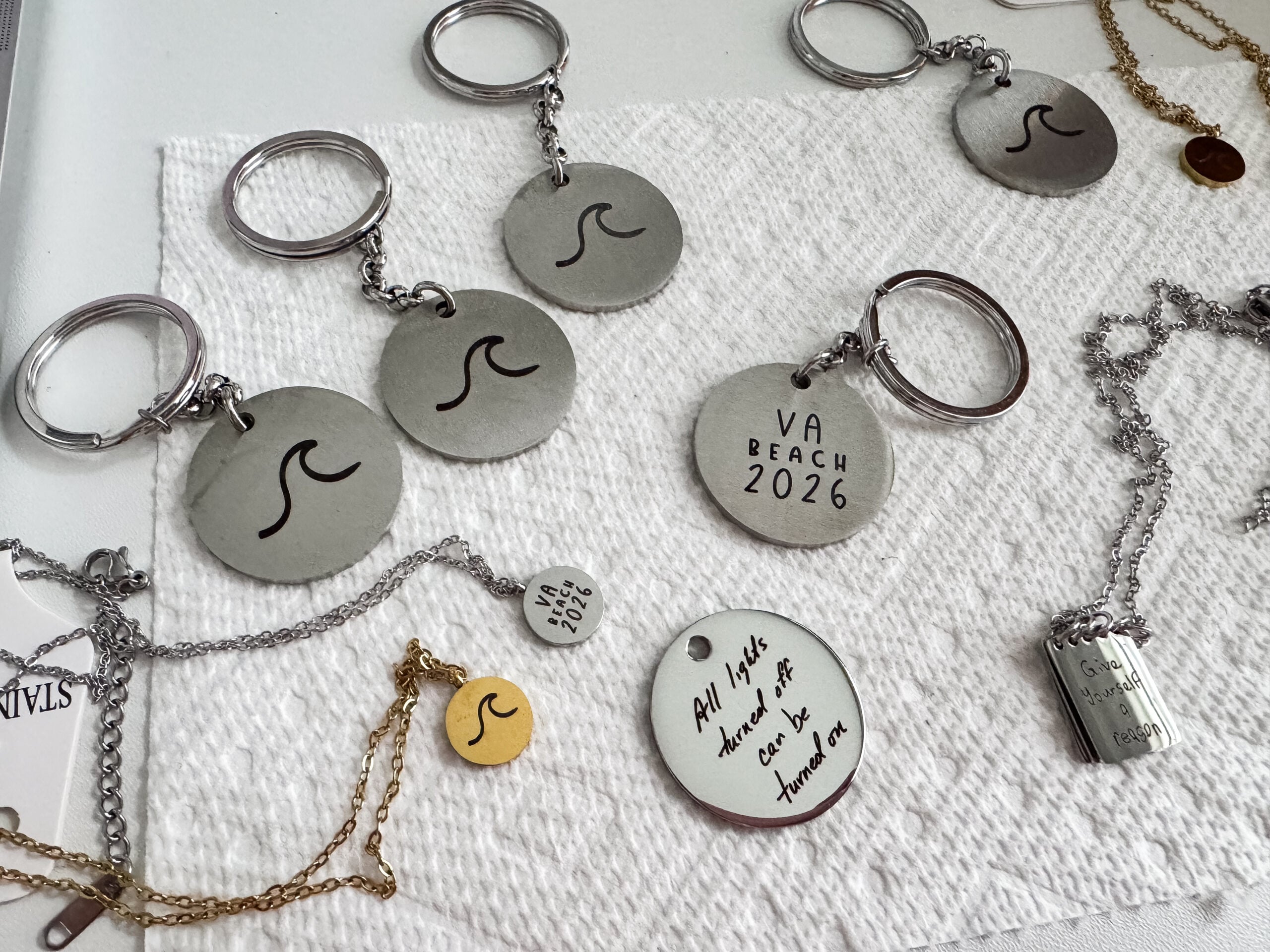 Collection of custom laser engraved keychains and necklaces made from handwriting and hand drawn designs