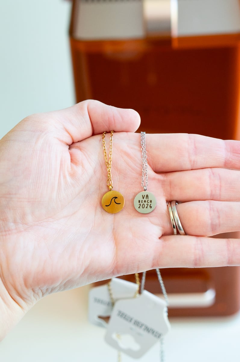 Close-up of two custom laser engraved necklaces featuring a wave design and VA Beach 2026