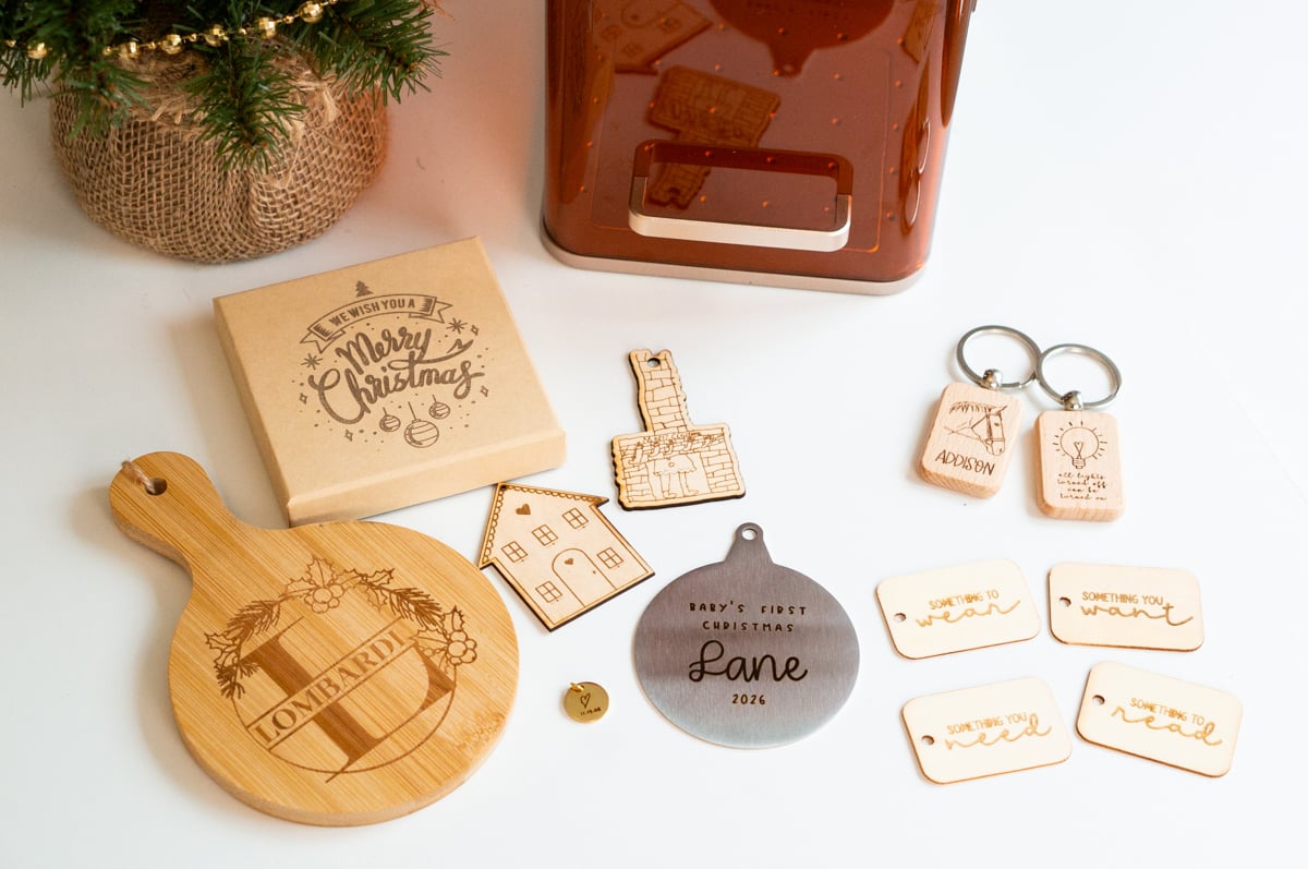 Collection of personalized Christmas gifts made with the xTool F2, including an engraved charcuterie board, Christmas gift box, wooden keychains, wooden ornaments, metal baby's first Christmas ornament, necklace charm, and wooden gift tags.